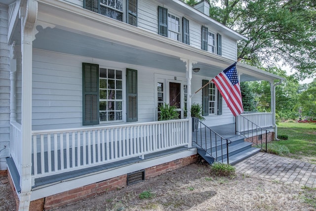 view of front facade featuring a porch, crawl space, and a chimney