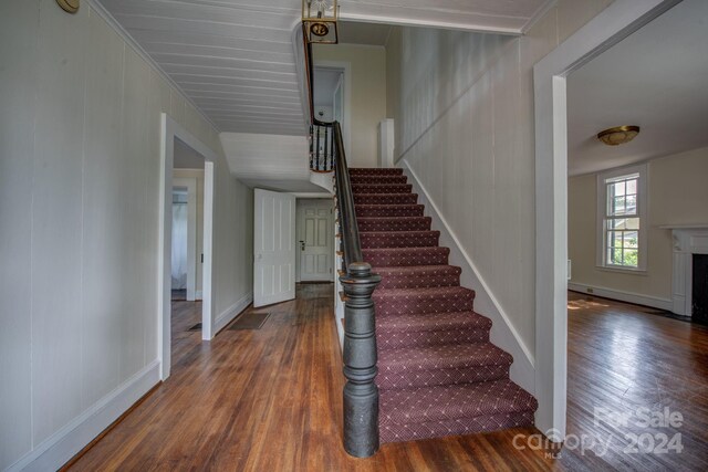 stairway with a fireplace with flush hearth and wood finished floors