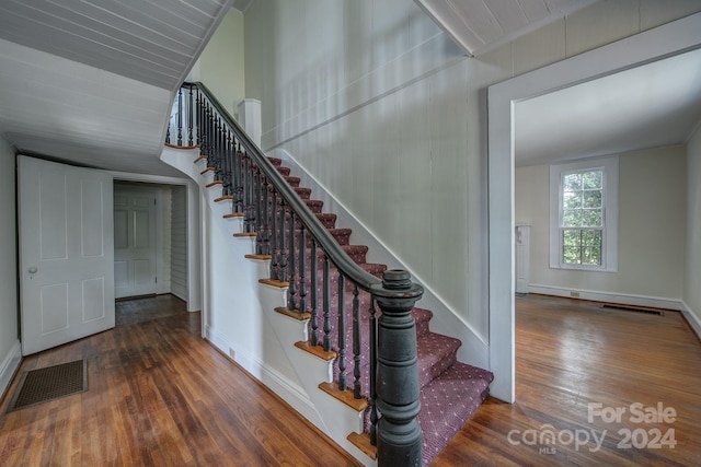 staircase featuring baseboards, visible vents, and wood finished floors