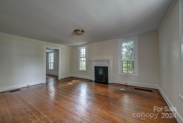 unfurnished living room with a fireplace with flush hearth, visible vents, dark wood finished floors, and baseboards