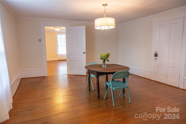 dining area with baseboards, ornamental molding, and wood finished floors