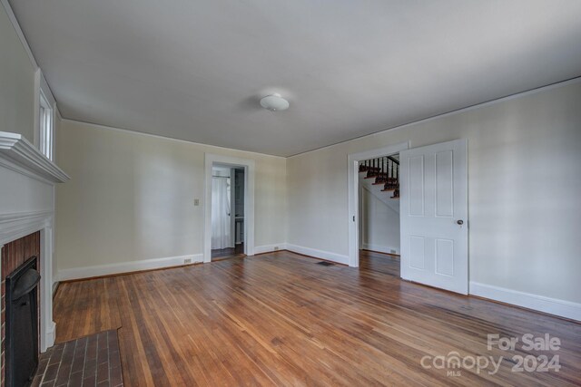 unfurnished living room with a fireplace with flush hearth, baseboards, and wood finished floors