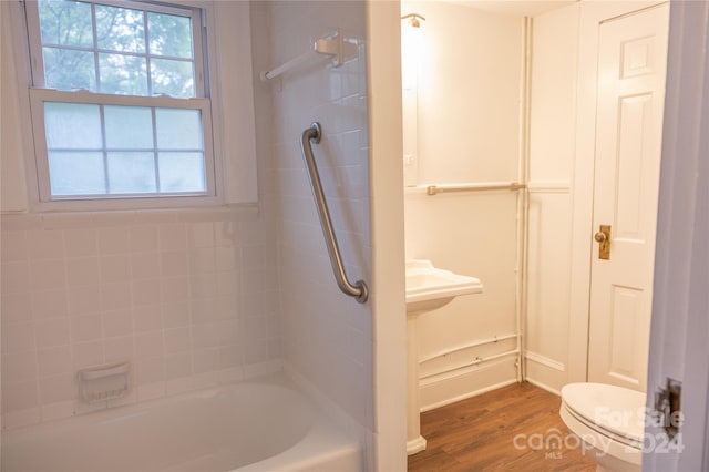 bathroom featuring a closet, bathing tub / shower combination, wood finished floors, and toilet