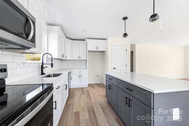 kitchen with sink, hanging light fixtures, gray cabinets, white cabinets, and appliances with stainless steel finishes