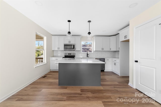 kitchen featuring appliances with stainless steel finishes, tasteful backsplash, pendant lighting, a center island, and white cabinetry