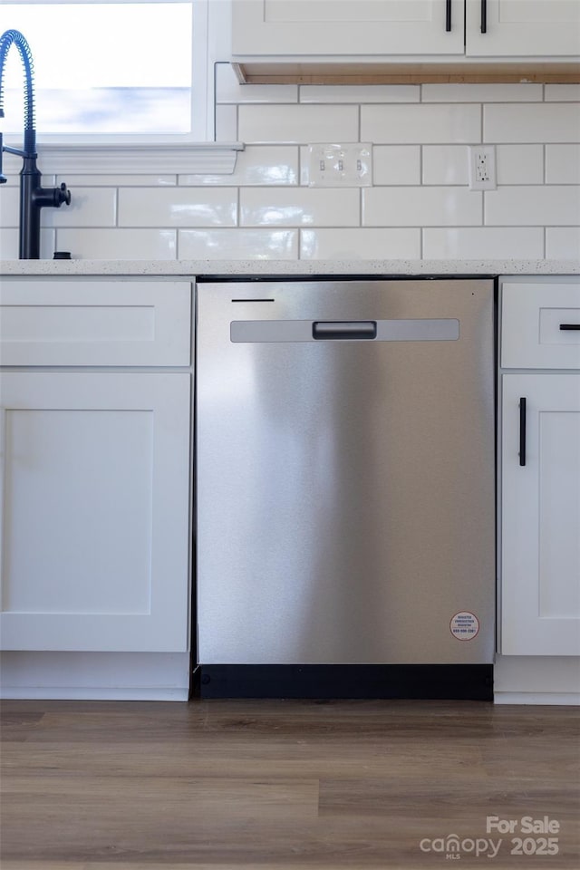 details with white cabinets, stainless steel dishwasher, light stone countertops, light wood-type flooring, and tasteful backsplash