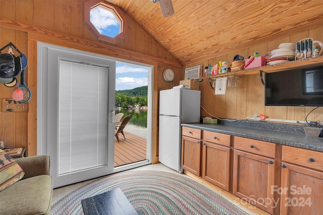 kitchen with ceiling fan, wooden walls, vaulted ceiling, and white fridge