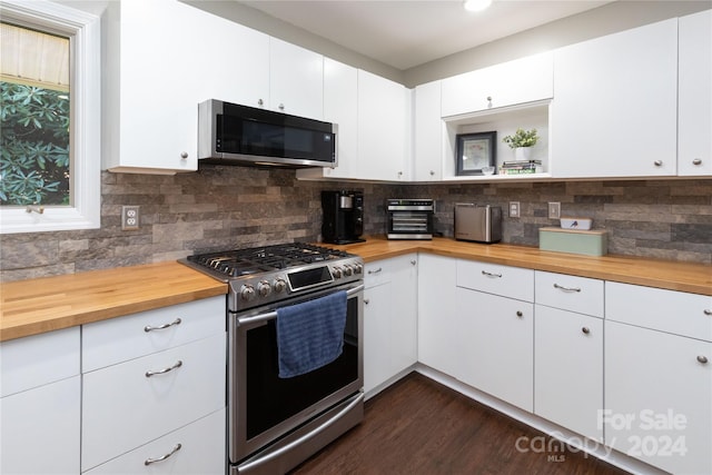 kitchen with stainless steel appliances, dark wood-style flooring, butcher block countertops, and backsplash