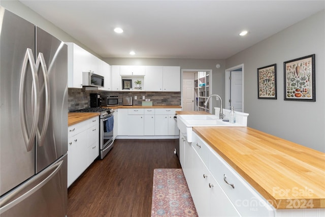 kitchen featuring butcher block counters, white cabinetry, appliances with stainless steel finishes, decorative backsplash, and dark wood-style floors