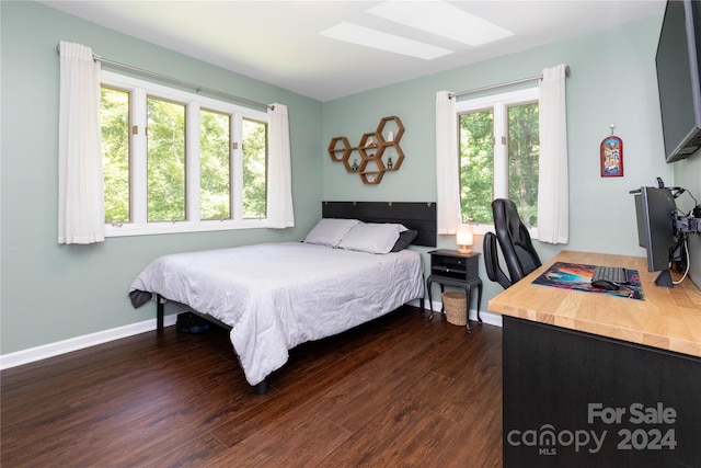 bedroom with dark wood-style flooring, a skylight, and baseboards