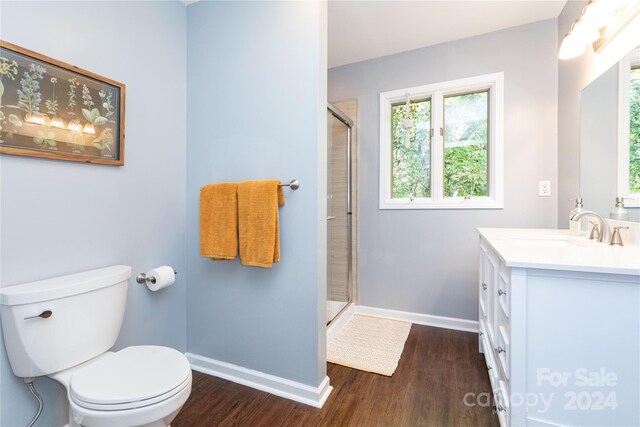 bathroom featuring toilet, wood finished floors, vanity, baseboards, and a shower stall