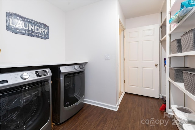 clothes washing area featuring dark wood-style floors, laundry area, washing machine and dryer, and baseboards