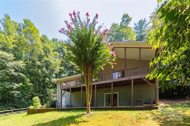 rear view of house featuring a wooden deck, a lawn, and fence