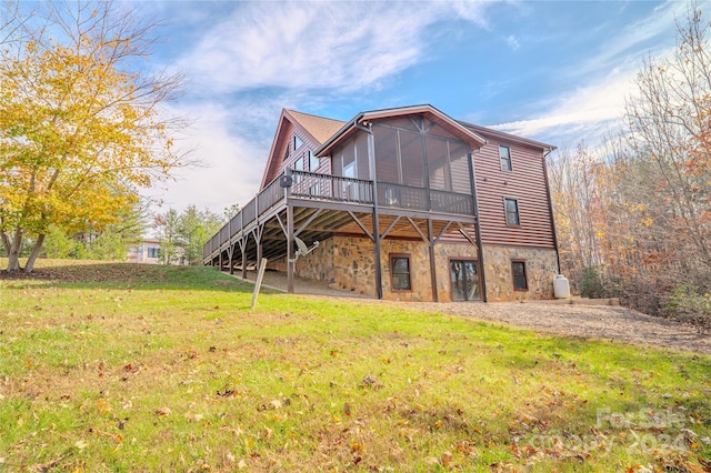 back of property with a lawn, a wooden deck, and a sunroom