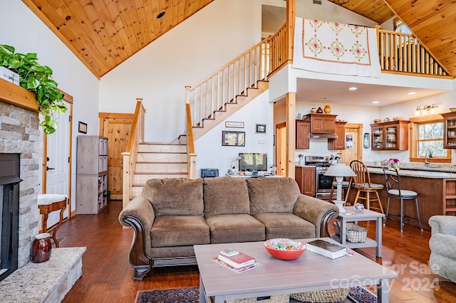 living room with wooden ceiling, high vaulted ceiling, dark wood-type flooring, and a stone fireplace