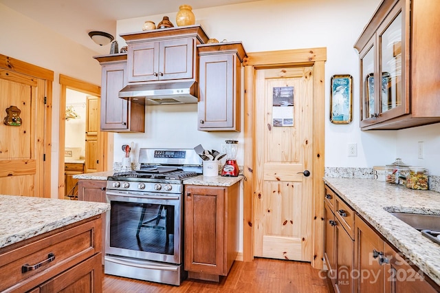 kitchen with light stone countertops, light hardwood / wood-style flooring, and gas range