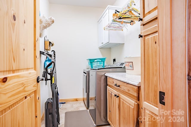 clothes washing area featuring cabinets and washing machine and dryer