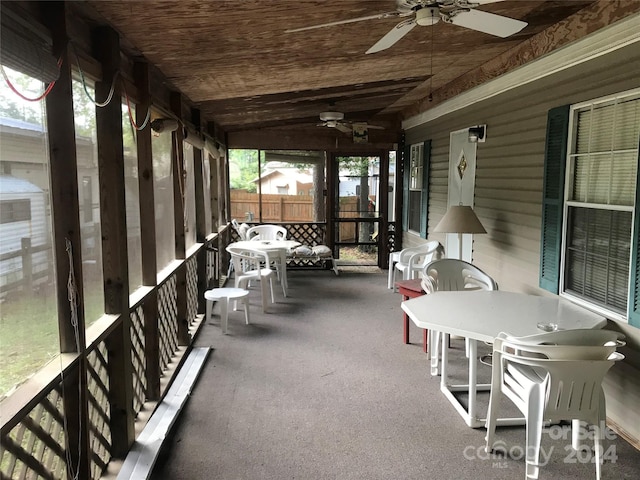 sunroom / solarium featuring vaulted ceiling, wooden ceiling, and a ceiling fan