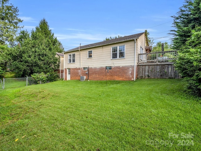 rear view of house with central AC unit and a yard