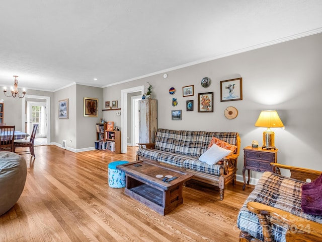 living room with crown molding, light wood-type flooring, and a chandelier