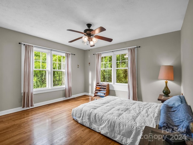 bedroom featuring light wood-type flooring, ceiling fan, and multiple windows