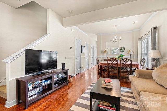 living room featuring hardwood / wood-style floors, ornamental molding, and a notable chandelier