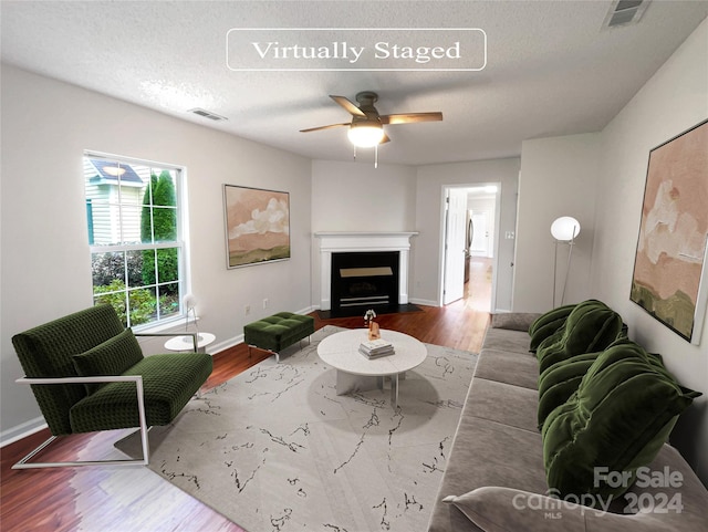 living room featuring hardwood / wood-style floors, a textured ceiling, and ceiling fan