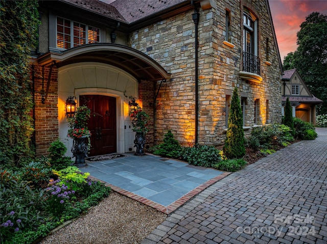 doorway to property featuring stone siding, a high end roof, and brick siding