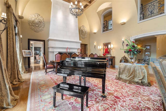 interior space featuring a fireplace, a high ceiling, wood finished floors, a chandelier, and baseboards