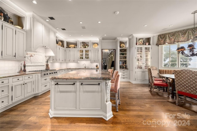 kitchen featuring white cabinetry, stainless steel gas stovetop, glass insert cabinets, and a center island