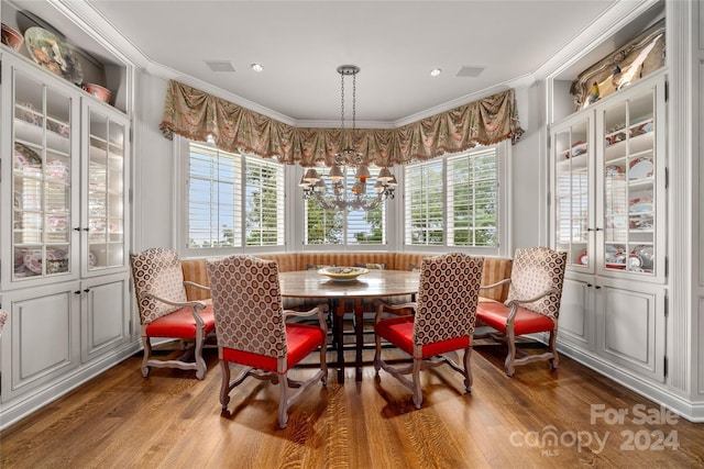 dining room with ornamental molding, a healthy amount of sunlight, a notable chandelier, and wood finished floors