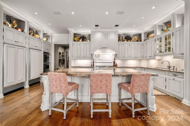 kitchen with open shelves, a center island with sink, and a kitchen breakfast bar