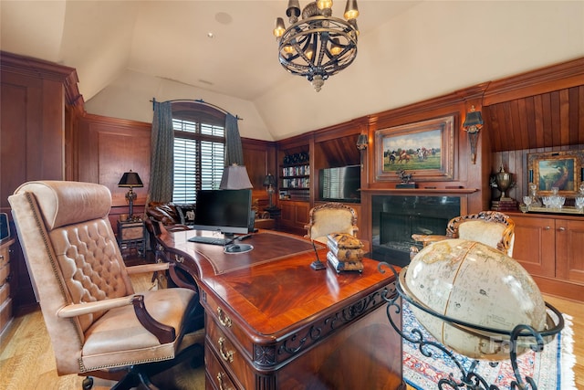 office featuring lofted ceiling, wooden walls, a premium fireplace, and a chandelier