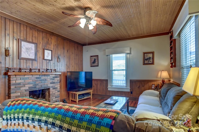 living room featuring wood walls, a fireplace, ceiling fan, wooden ceiling, and hardwood / wood-style flooring