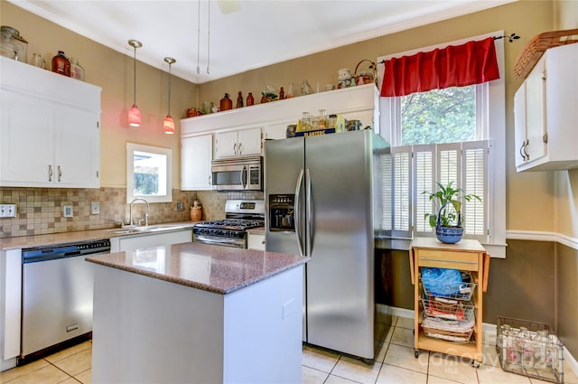 kitchen featuring decorative backsplash, hanging light fixtures, white cabinetry, appliances with stainless steel finishes, and sink