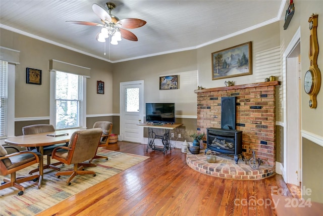 dining space featuring ceiling fan, crown molding, hardwood / wood-style floors, and a wood stove