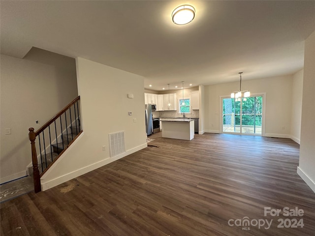 unfurnished living room featuring sink, dark hardwood / wood-style flooring, and a chandelier