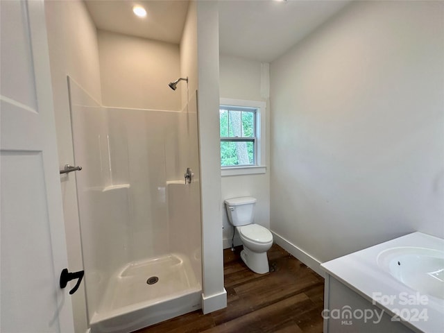 bathroom featuring wood-type flooring, a shower, vanity, and toilet