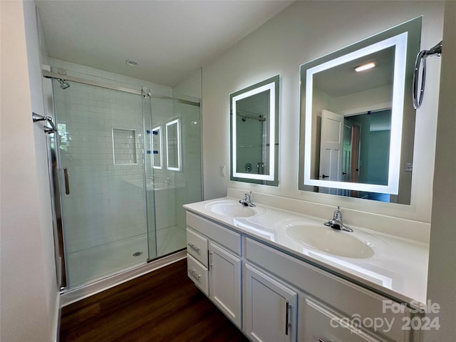 bathroom featuring dual vanity, a shower with door, and hardwood / wood-style floors