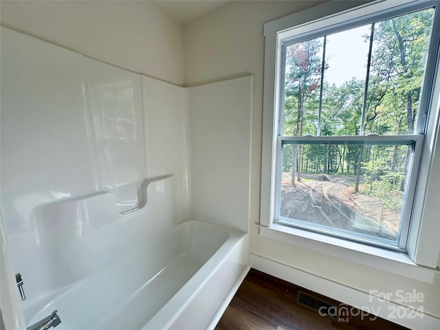 bathroom with plenty of natural light, hardwood / wood-style flooring, and shower / washtub combination