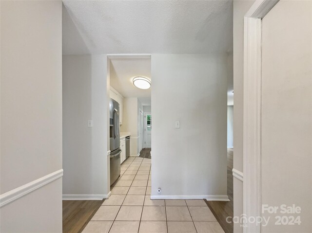 hall featuring light tile patterned flooring and a textured ceiling