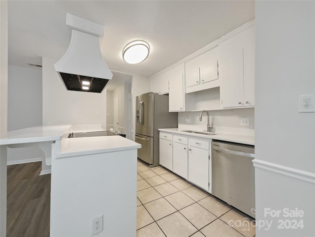 kitchen featuring sink, stainless steel appliances, custom range hood, white cabinets, and kitchen peninsula