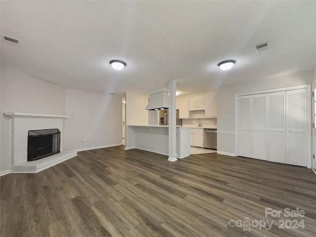 unfurnished living room featuring dark wood-type flooring, a fireplace, and sink