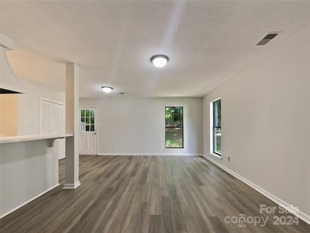 unfurnished living room featuring dark hardwood / wood-style floors and a textured ceiling