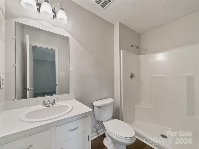 bathroom featuring walk in shower, vanity, and toilet