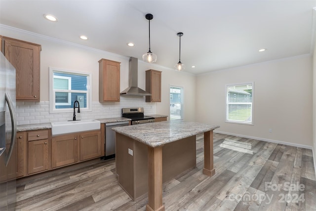 kitchen featuring sink, wall chimney exhaust hood, decorative backsplash, a kitchen island, and stainless steel appliances