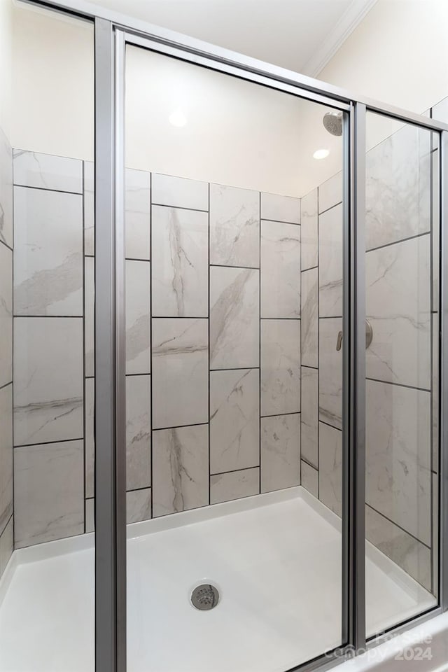 bathroom with ornamental molding and an enclosed shower