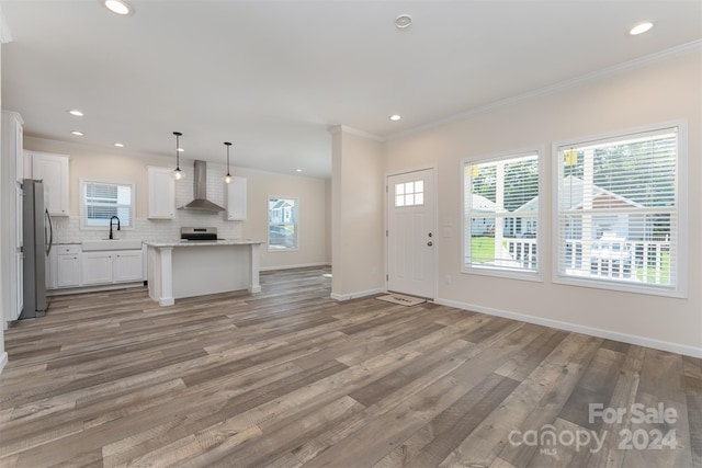 unfurnished living room featuring hardwood / wood-style flooring, sink, and crown molding