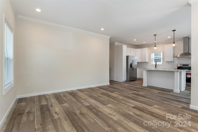 unfurnished living room featuring hardwood / wood-style flooring, sink, and crown molding