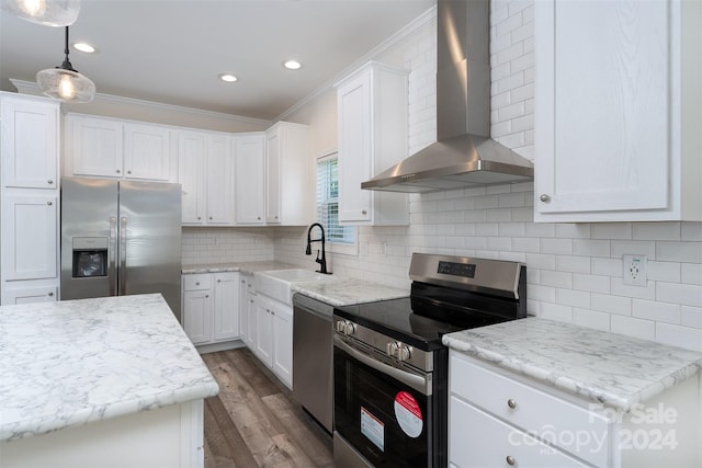 kitchen with backsplash, wall chimney exhaust hood, ornamental molding, appliances with stainless steel finishes, and decorative light fixtures